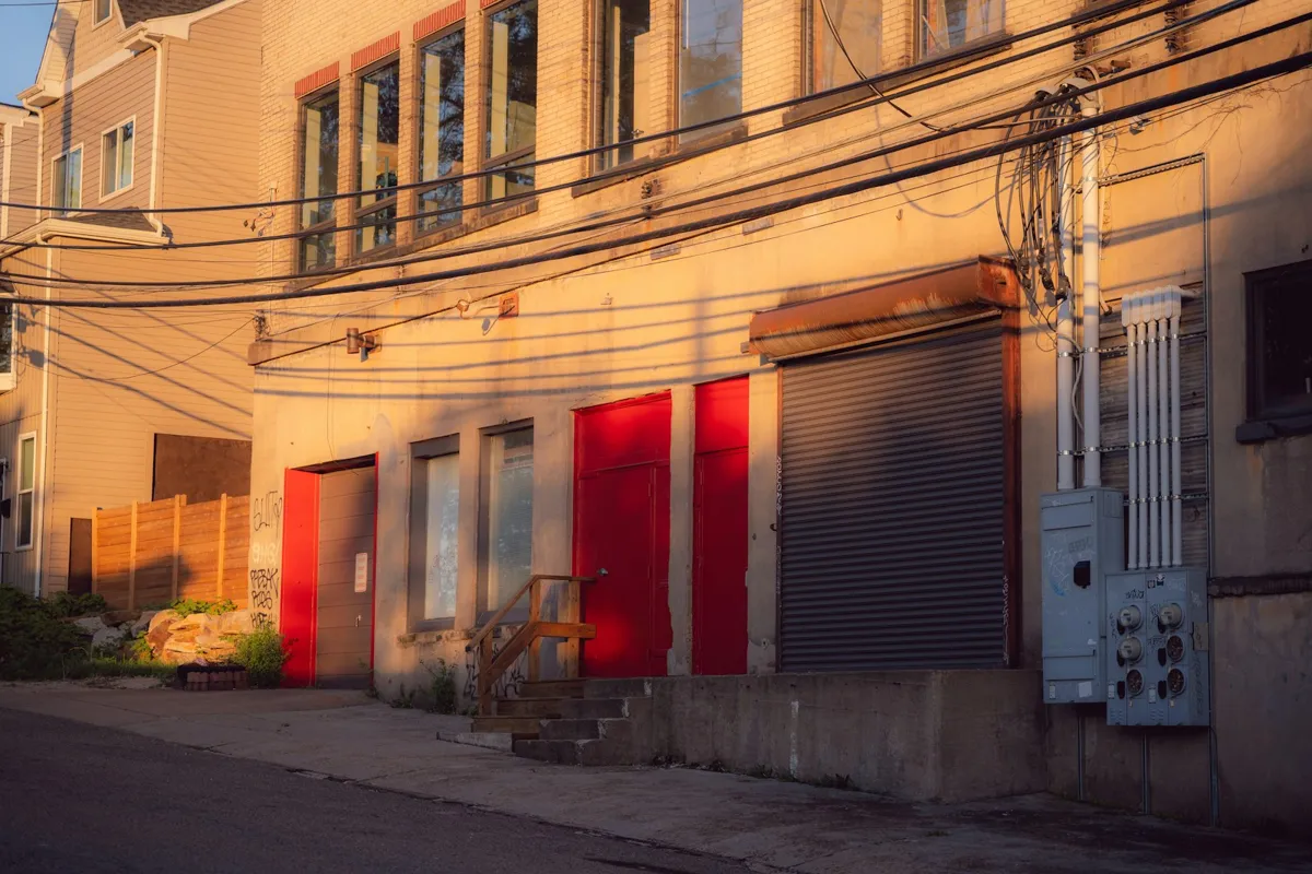 Alley with red service doors and a roll-up door at sunset