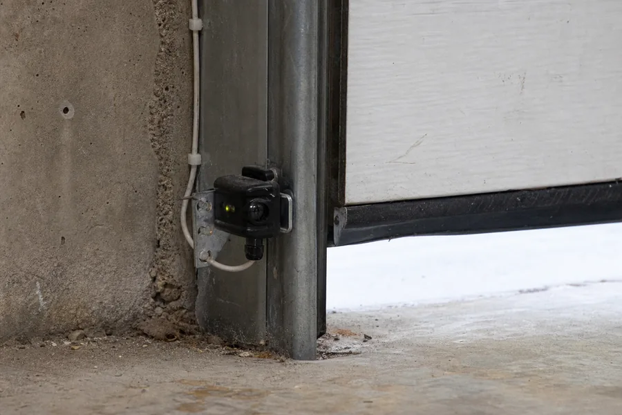 Photo-eye safety sensor at the base of a garage door track in Topeka, KS