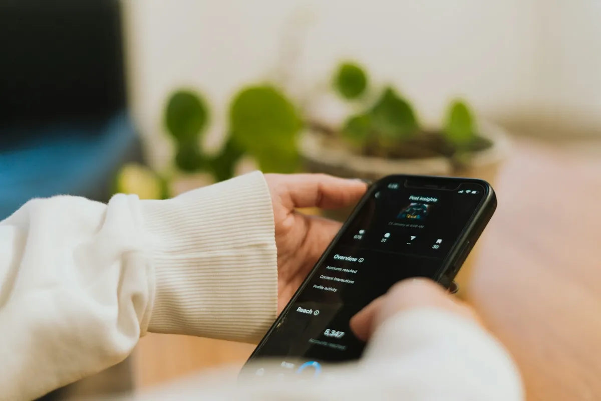 Hand holding a phone with a dark app screen